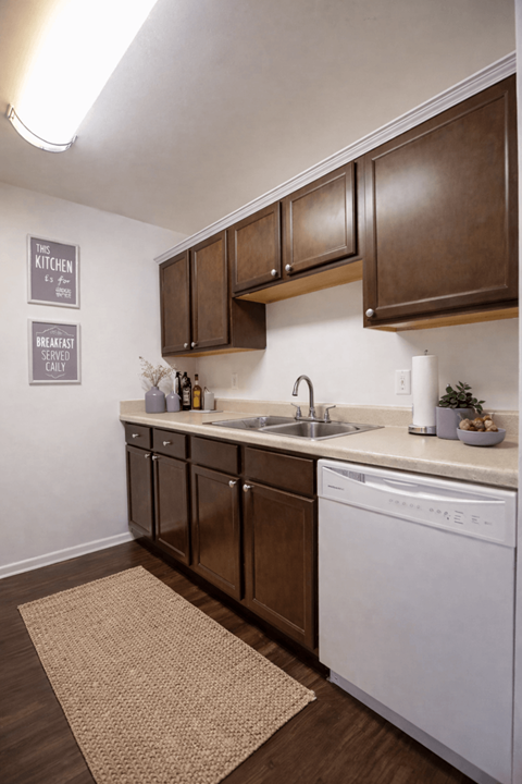 A kitchen with brown cabinets and a white dishwasher.
