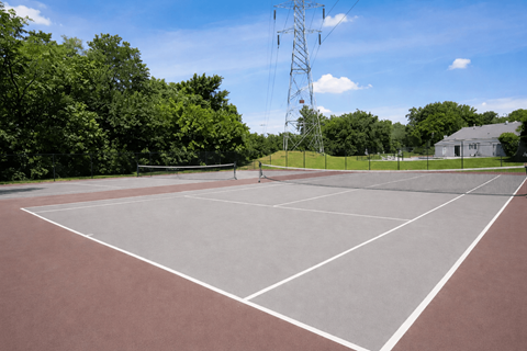 A tennis court with a net and a tall tower in the background.