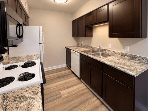 A kitchen with a white stove top and brown cabinets.