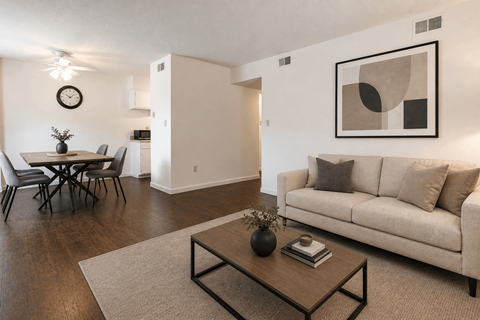 A living room with a couch, a dining table, and a painting on the wall.