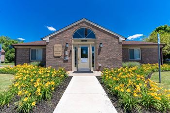 the front of a brick church with a sidewalk and yellow flowers