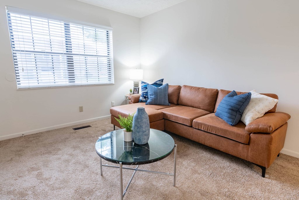 a living room with a brown couch and a glass coffee table