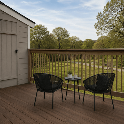 Two black chairs are on a wooden deck with a table between them.