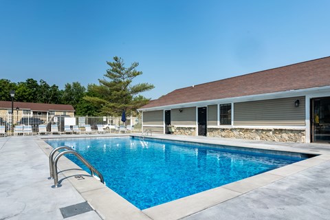 A swimming pool with a diving board and a building in the background.