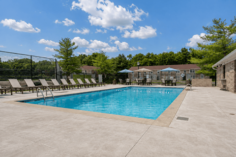 A large outdoor swimming pool surrounded by a fence and lounge chairs.