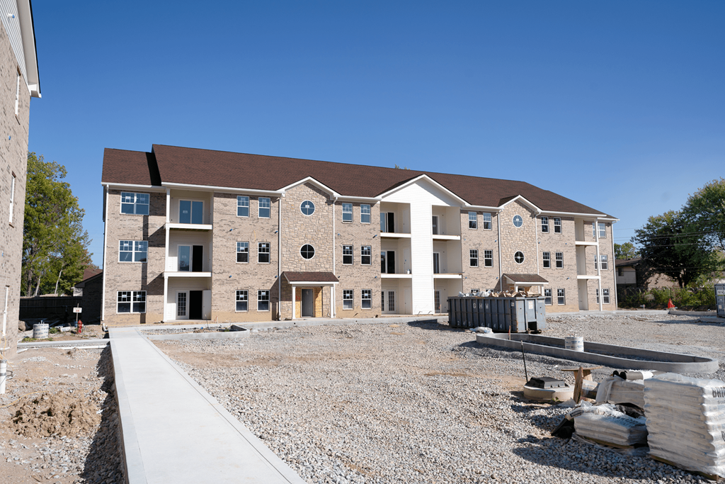 a large brick apartment building with a gravel yard in front of it