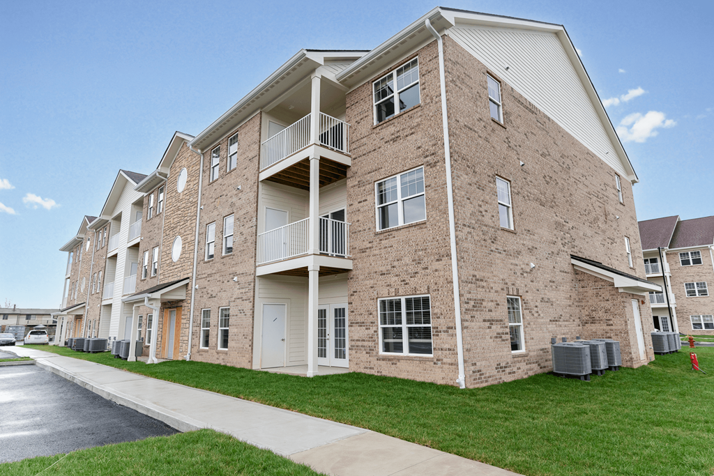 a brick apartment building with balconies and a sidewalk