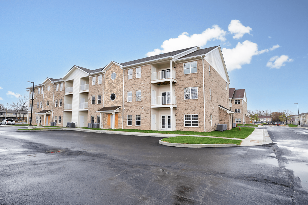 the view of a brick apartment building with a parking lot