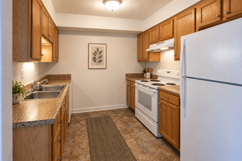 A kitchen with a white refrigerator, sink, and stove.