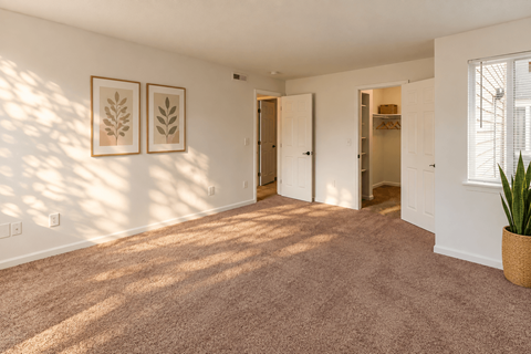 A room with a carpeted floor and two framed leaves on the wall.