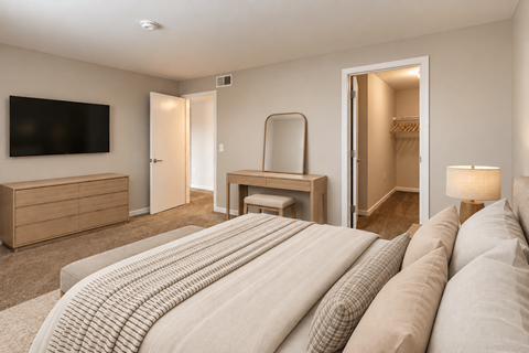 A bedroom with a large bed and a flat screen TV mounted on the wall.