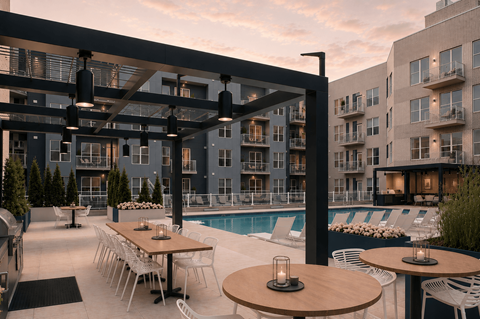 A modern outdoor dining area with tables and chairs is set up next to a pool at The Whit Apartments, Indianapolis, IN, 46204