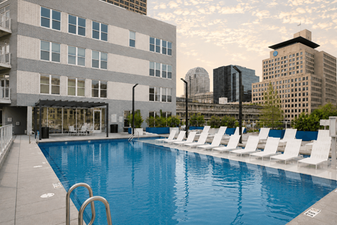 A large swimming pool with white chairs and a building in the background at The Whit Apartments, Indianapolis, IN, 46204