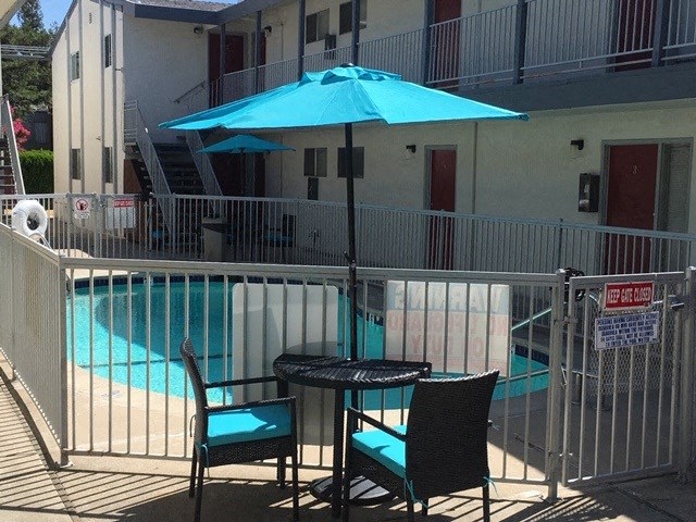 a table and chairs under an umbrella next to a swimming pool