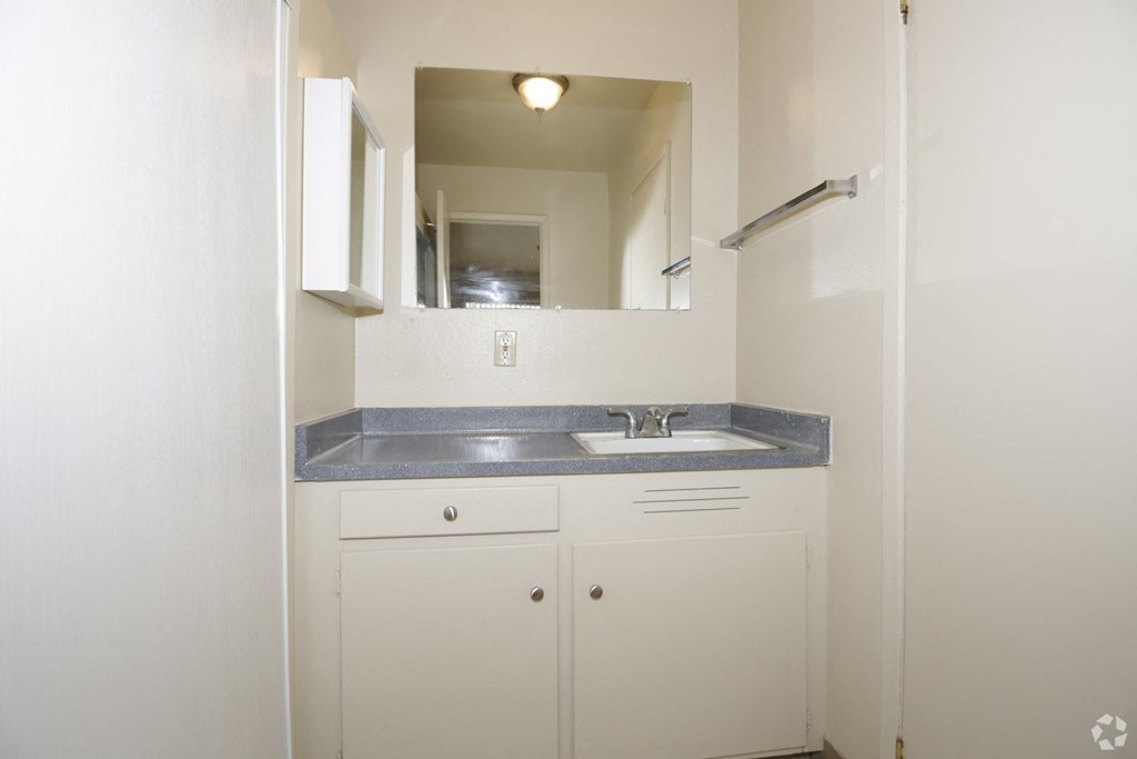 a bathroom with white cabinets and a sink and a mirror