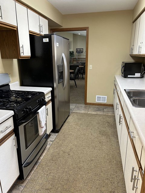 A kitchen with a black refrigerator and white appliances.