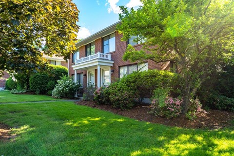 exterior view of a brick apartment building with green grass and trees