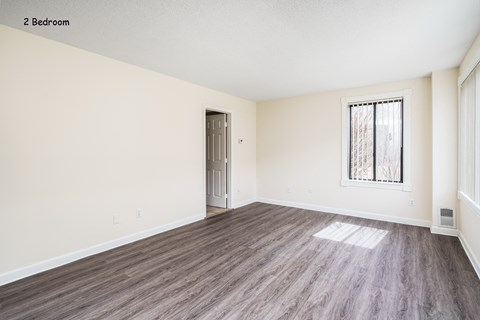an empty living room with wood flooring and a window