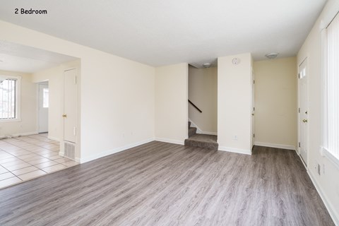 an empty living room with wood flooring and white walls