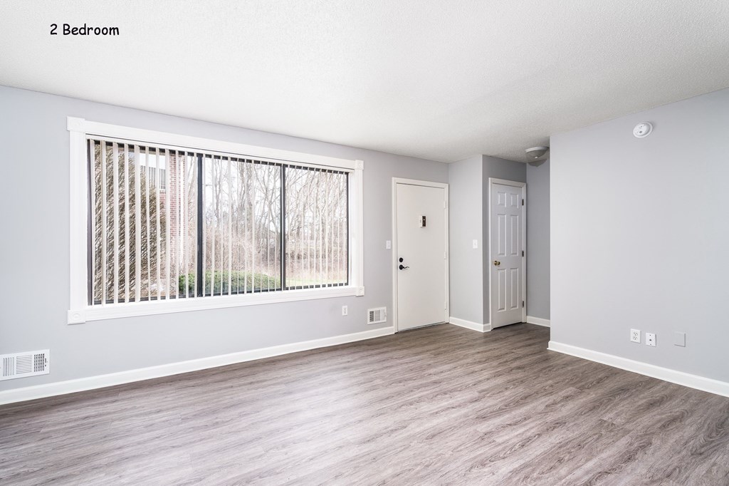 an empty living room with a large window and wood flooring