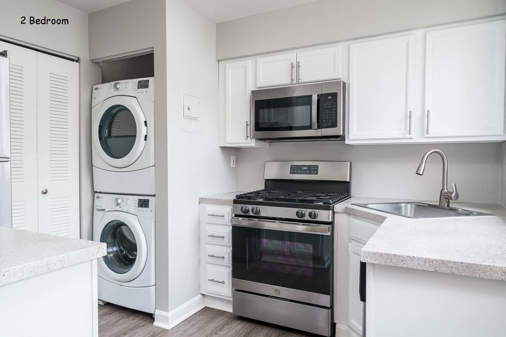 a white kitchen with stainless steel appliances and white cabinets