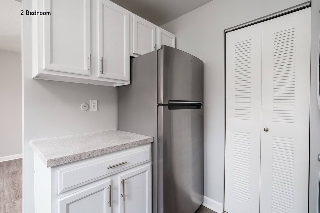 a kitchen with white cabinets and a stainless steel refrigerator