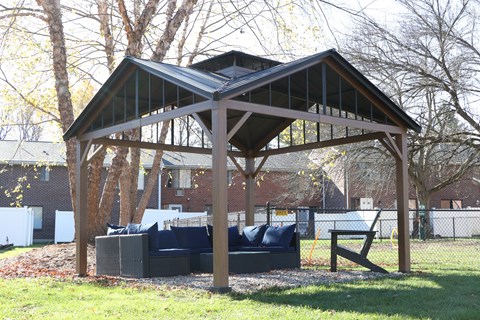 a covered patio with a couch in a backyard