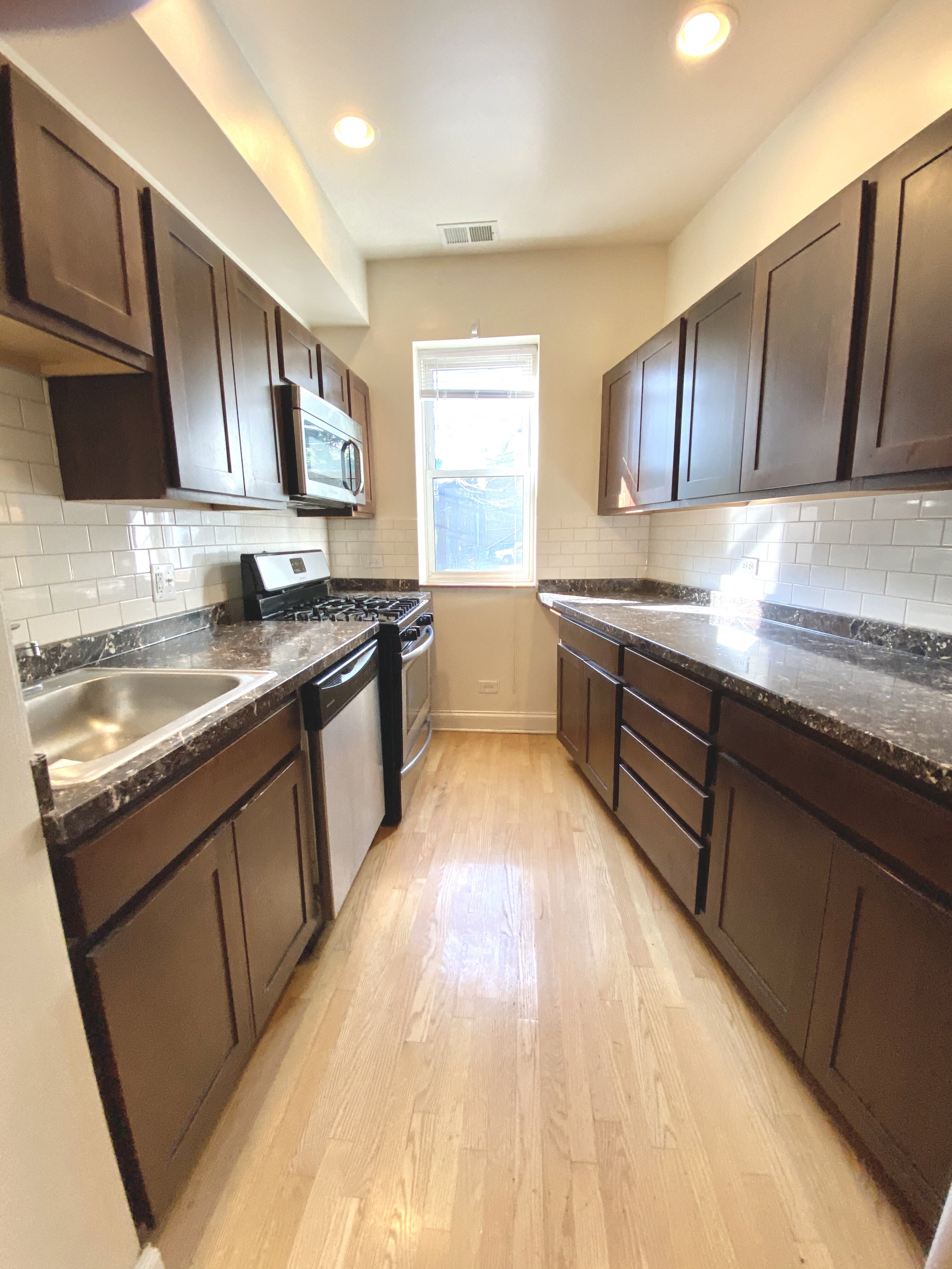 a large kitchen with wooden floors and black cabinets