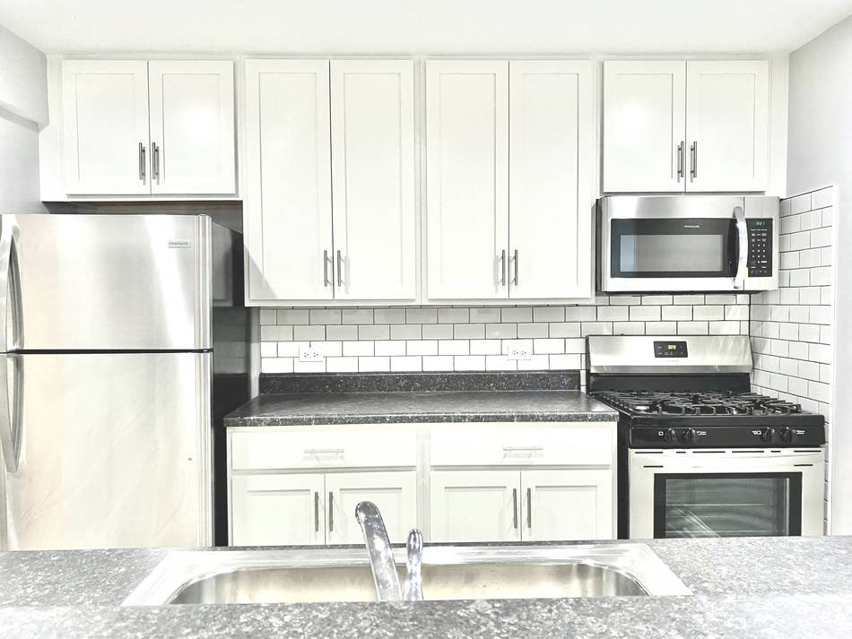 a white kitchen with stainless steel appliances and white cabinets