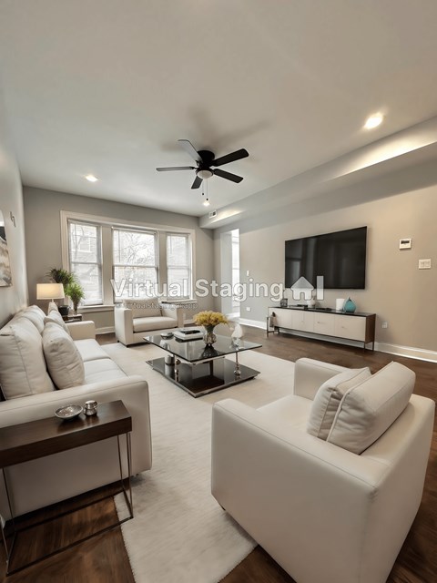 a large living room with white couches and a tv