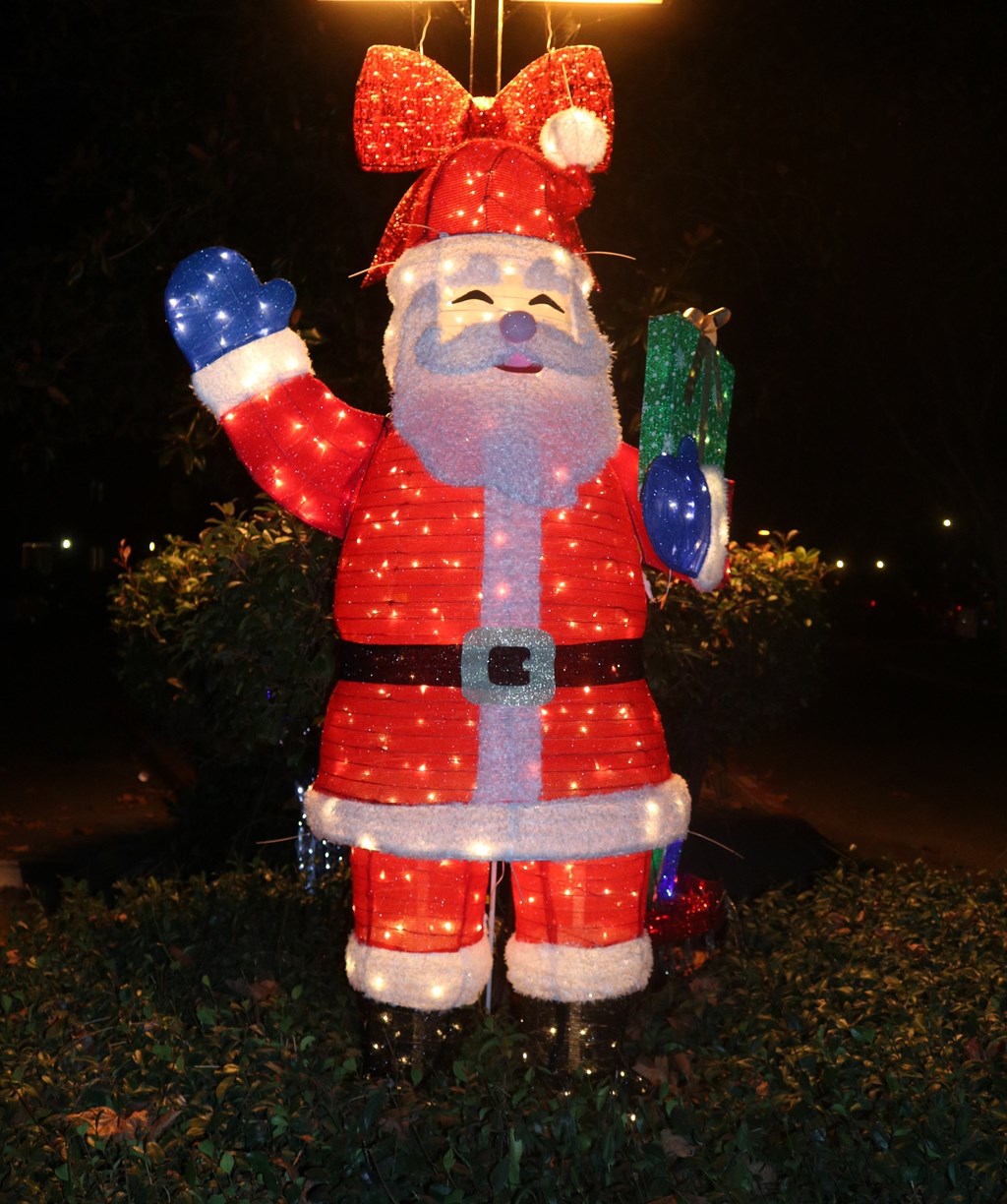 A lighted Santa Claus statue is standing in the grass.