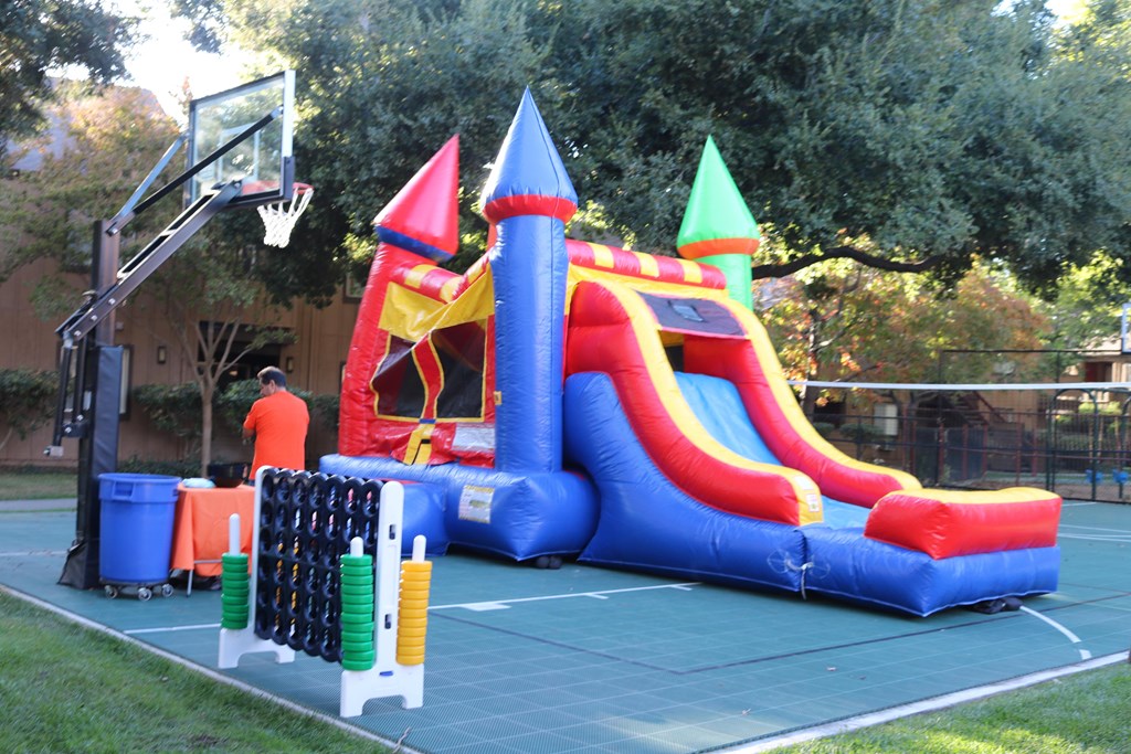 A large inflatable bounce house with a slide and a basketball hoop.