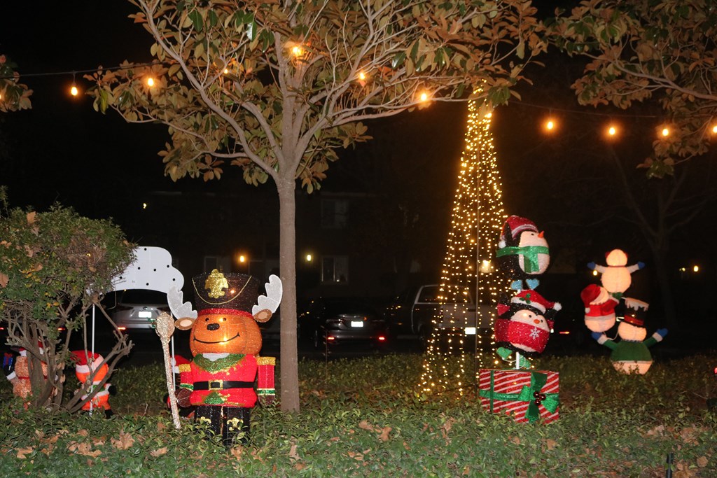 A Christmas tree is lit up at night with a nutcracker in front of it.