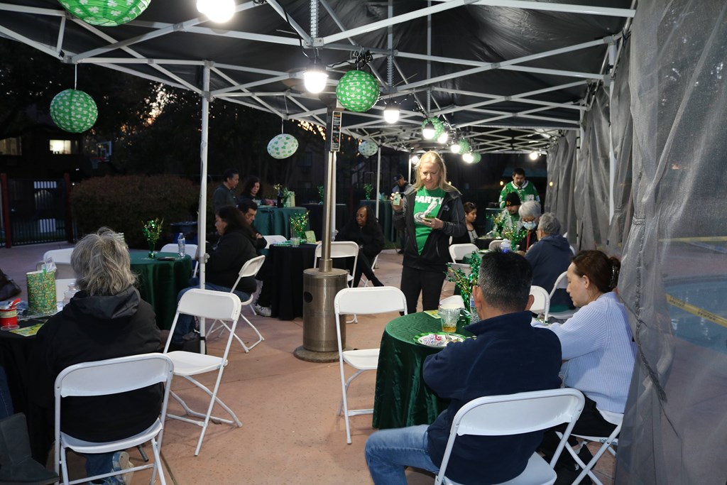 A group of people are gathered under a tent with green and white decorations.