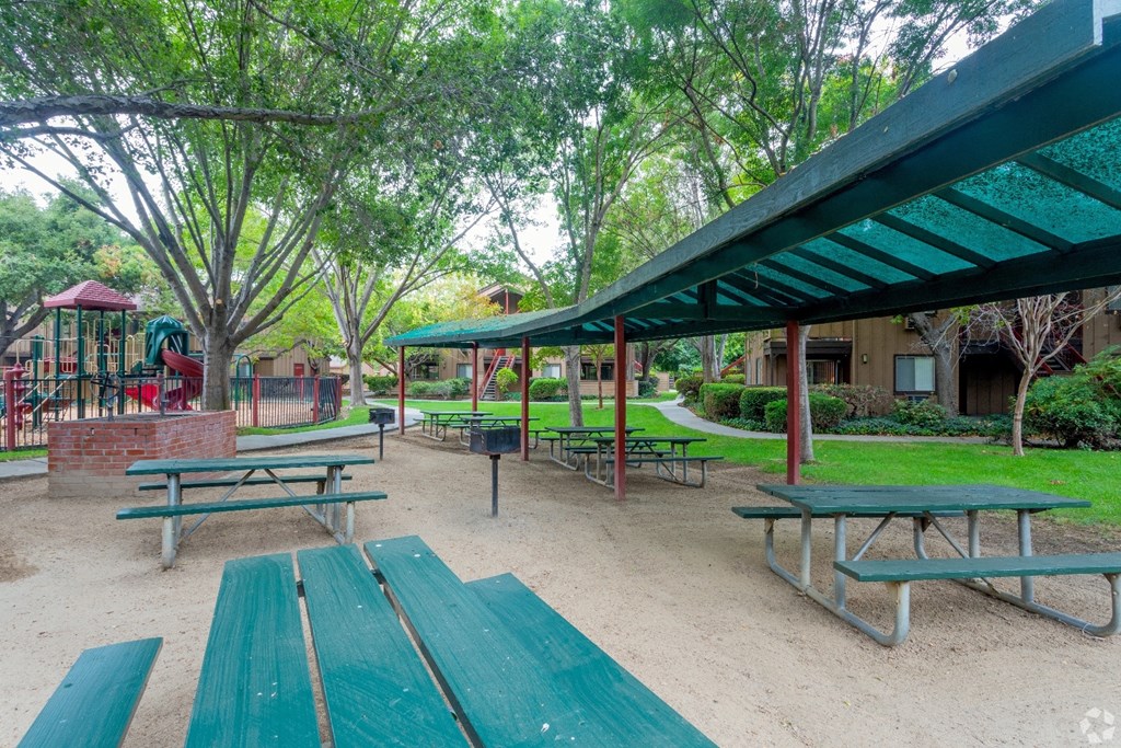 BBQ Area and playground with green benches and a red structure.