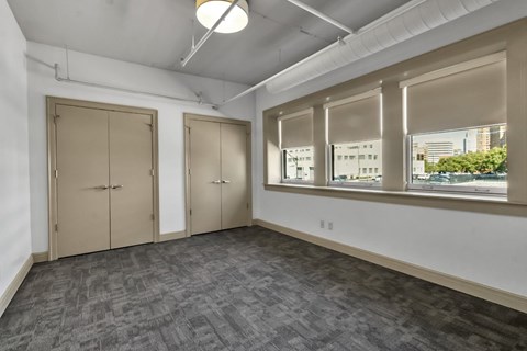 A room with grey carpet and three closed doors.