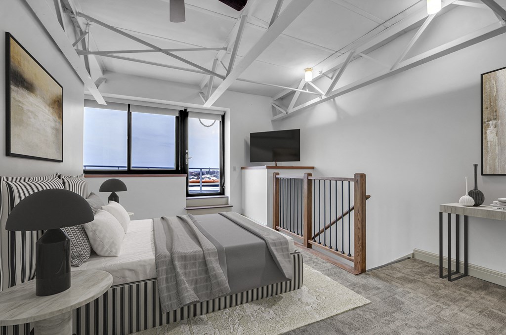 A modern bedroom with a large bed and a television. at 100 South Apartments, Buffalo, NY