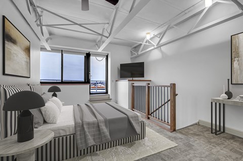 A modern bedroom with a large bed and a television. at 100 South Apartments, Buffalo, NY