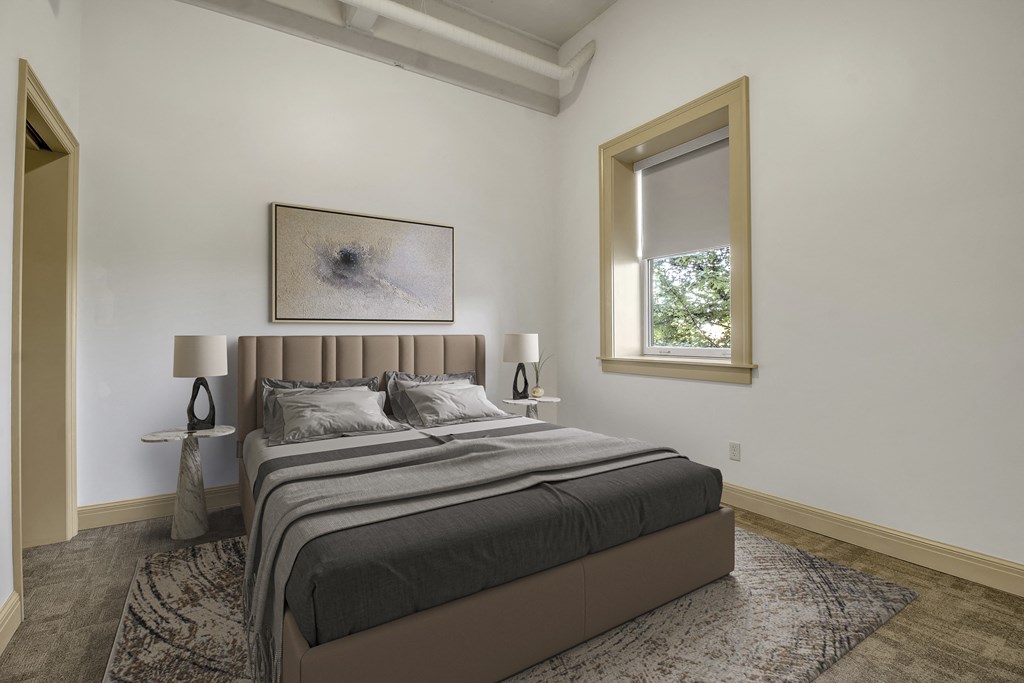 A bedroom with a large bed and a painting on the wall. at 100 South Apartments, New York, 14202