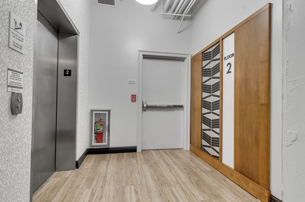 A hallway with a door on the right and a stairwell on the left.