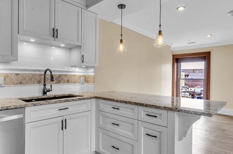 A kitchen with a marble countertop and white cabinets at The Knights @ 506 Delaware Apartments, Buffalo