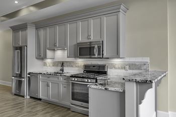 A modern kitchen with a marble countertop and stainless steel appliances.