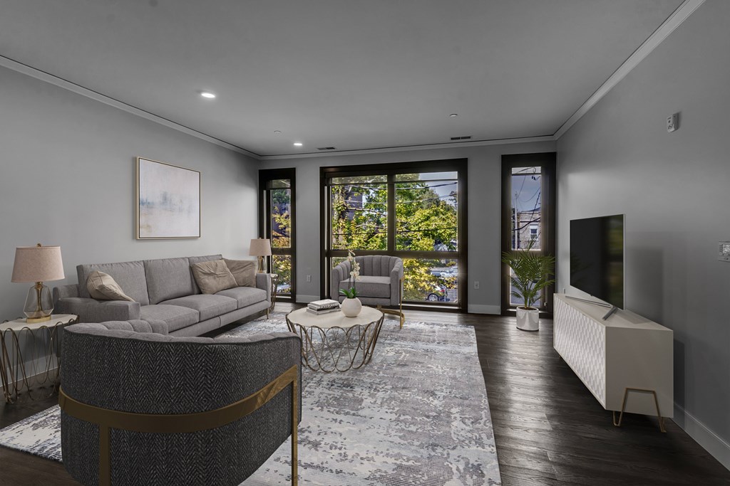 A modern living room with a grey sofa and a grey rug.