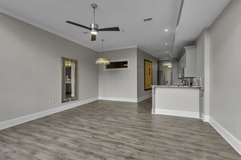 A spacious room with a ceiling fan and a chandelier.