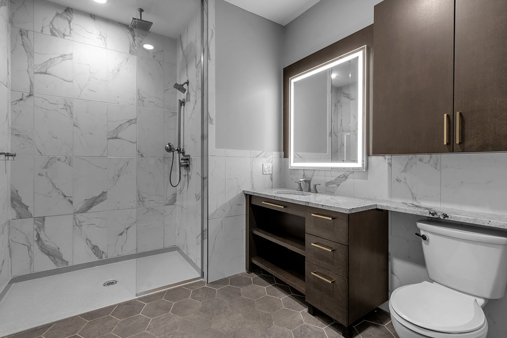 A bathroom with a marble tile shower and a white toilet.