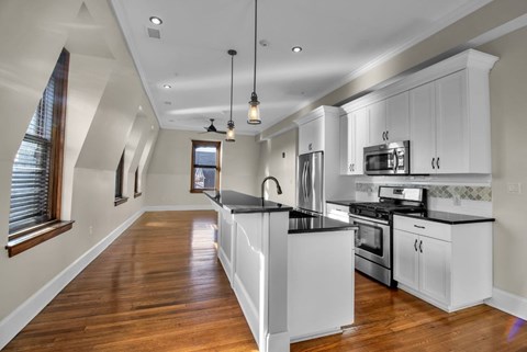 A modern kitchen with white cabinets and a wooden floor.