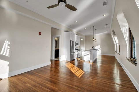 A spacious kitchen with wooden floors and a ceiling fan.