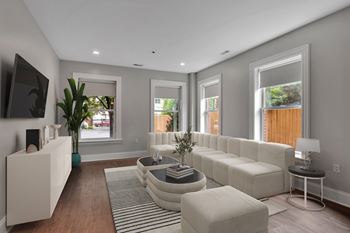 A modern living room with a white sofa set and a flat screen TV.
