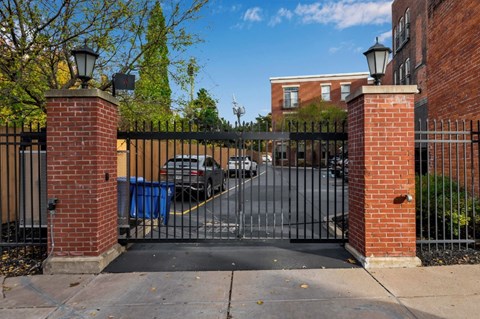 A black gate with brick pillars blocks the road.