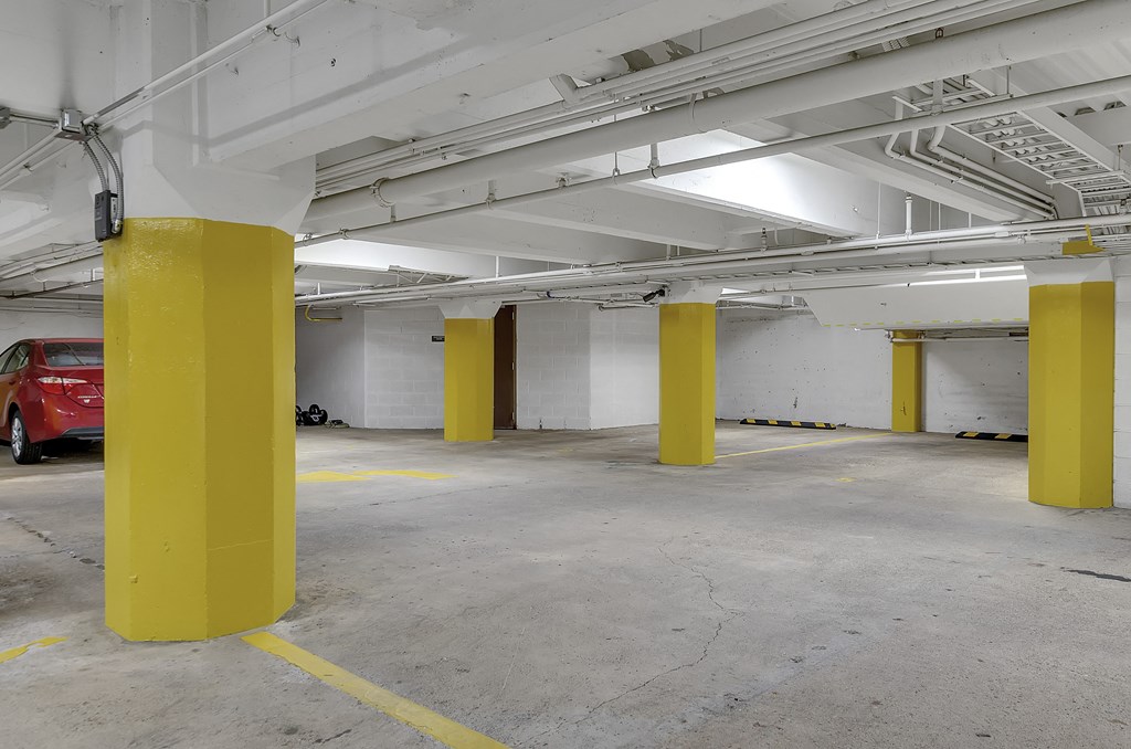 a parking garage with yellow pillars and a red car at 100 South Apartments, New York, 14202